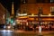 Eiffel tower illuminated at night and street with people and typical restaurant in Paris, France