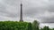 The Eiffel Tower over trees with stormy clouds