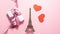 The Eiffel Tower, red hearts and white gift with purple ribbon bow on bright background. Stop motion animation with copy space.