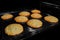 Eight baked crunchy oatmeal cookies on metal sheet in oven