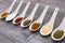 Eight ceramic spoons lined up in a line filled with colorful spices