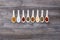 Eight ceramic spoons lined up in a line filled with colorful spices