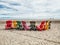 Eight many colorful red, brown and yellow wooden muskoka Adirondack chairs in row on beach outside