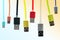 Eight multicolored usb cables hang vertically, on a gradient, tinted background. The family unites. future technologies.