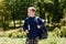 Eight-year-old handsome schoolboy with book armpit and a backpack on his shoulder on a blurr natural background