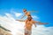 Eight years old boy sitting on dad`s shoulders. Both in swimming shorts and sunglasses, having fun on the beach. Bottom view