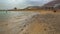 Ein Bokek, Israel - January 22, 2020: Calm day at Ein Bokek Dead Sea beach, blue green water, sunshade shelter near, sun shines on