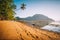 El Nido village coastline, with sandy beach and palm trees and local boats in shallow lagoon at golden sunset light