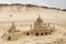 Elaborate medieval sandcastle on beach with dunes in the background