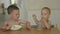 elder brother feeding his young baby sibling pasta from hands, boys sitting eat