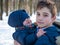 Elder brother hold in arms his young brother at winter park background