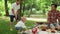 Elder brother playing with toddler in park. Happy family having picnic outdoors