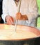 Elder cheesemaker boiling milk into the mixing pot for making ch