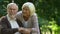 Elder couple hugging and happily watching on their grandchildren playing in park