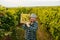 elder male farmer winegrower hold lift box of grapes on shoulder great harvest, smiling