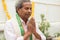 Elder man in closed eyes offering Prayer by namaste gesture praying to god at home in traditional dress during rituals.