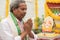 Elder man offering Prayer by namaste gesture in front of Lord Ganesha Idol during Ganesha or vinayaka Chaturthi festival