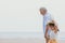 Elder man walking with grandchild at sea beach outdoors with white space for text, old man care children concept