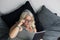 An elder obese woman laying on the bed looks at a tablet