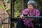 Elder woman holding mobile phone on terrace. elderly female text