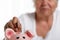 Elder woman putting pin money coins into pink piggybank slot