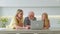 Elderly 70 years old gray-haired old pensioner learns to use modern laptop. Smiling young woman and daughter show an old