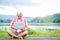 An elderly Asian man sitting and typing a notebook working outdoors