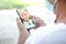 Elderly Asian man wearing a mask Use a smartphone to chat with niece via video call.