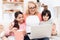 Elderly beautiful woman looks at laptop laughing with her little grandchildren.