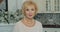 Elderly, beautiful woman smiling looking at the camera. Portrait of senior adult retired lady grandma on the kitchen