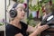 An elderly blonde woman 60-65 years old in old headphones holds a vinyl record in her hands, a record player against the backgroun