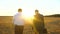 An elderly businessman in serious suit with briefcase in his hand gives work plan to company employee in evening in