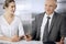 Elderly businessman and woman sitting and communicating in office. Adult business people or lawyers working together as