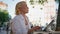 Elderly businesswoman typing laptop at sunny street cafe closeup. Serious senior