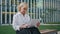 Elderly businesswoman typing text on laptop sitting street bench close up.