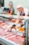 Elderly butcher shop salesman offering chorizo and chistorra sausages