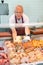 Elderly butcher shop seller laying out raw chickens in display case