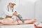 Elderly butcher in uniform cutting pork carcass with knife.