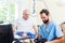 Elderly care nurse helping senior from bed to wheel chair