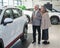 An elderly Caucasian couple chooses a new car at a car dealership.