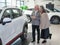 An elderly Caucasian couple chooses a new car at a car dealership.