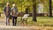 Elderly Caucasian couple walk in the park disabled blind man in glasses uses a stick and his wife helps him to go