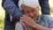 elderly caucasian gray-haired woman hugs her husband\'s hand and gently strokes it