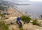 Elderly caucasian male Amerasian tourist posing on Tete de Chien, with a vew of Monaco in the background.