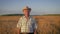 Elderly caucasian man in a cowboy hat walk in a field of wheat at sunset
