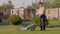 Elderly caucasian man gardener stands on a green lawn and holds a lawn mower