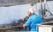 Elderly Caucasian man painting a boat on a sunny day