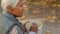 Elderly Caucasian woman eats soup in the park looking away fall medium closeup selective focus copy space