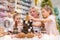 Elderly caucasian woman making pine cones decoration for christmas with two granddaughters