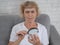 Elderly Caucasian woman with myopia and trying to read a message on a smartphone using a magnifying glass.